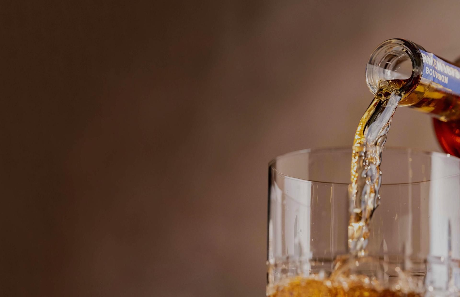 barmen bottle pouring whiskey on glass